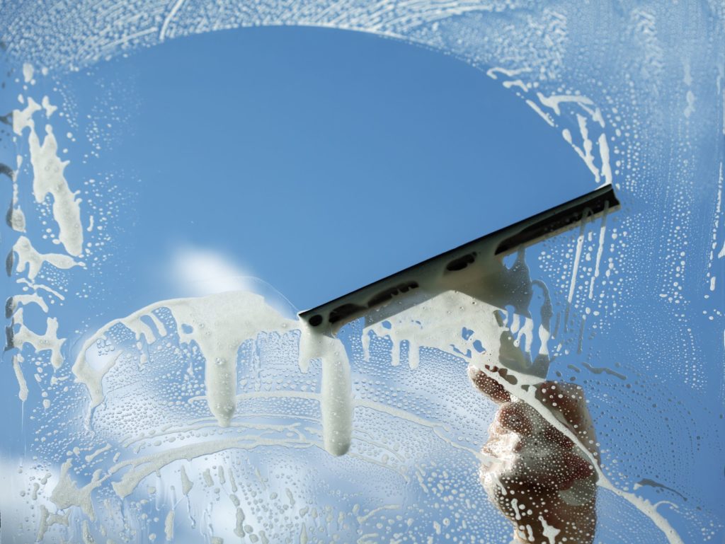 A crescent-shaped motion is used to clean a window with a squeegee.